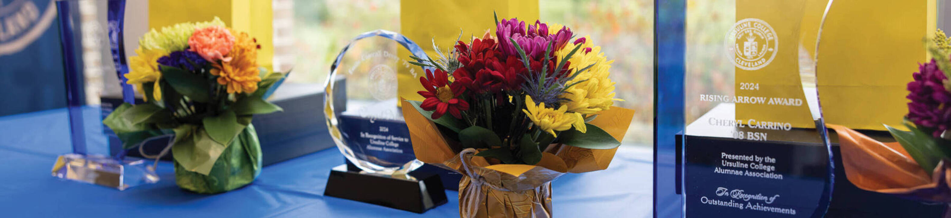 Image of table holding the three Ursuline College alumni awards and flowers